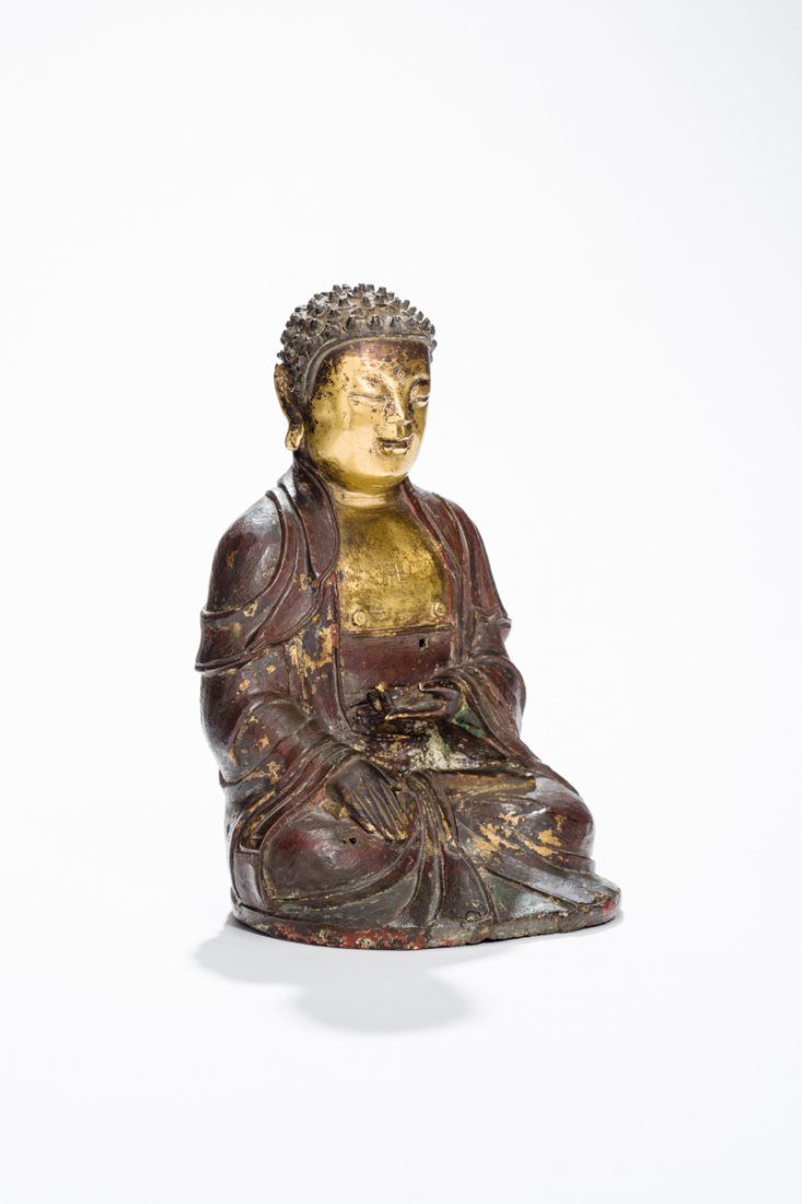 SEATED BUDDHA SHAKYAMUNI: Bronze with gilding. China, Ming Dynasty (1368 â€“ 1644) A neat small bronze sculpture with a unique expression. The historical Buddha is seated in padmasana, holding one hand on his lap, the oth