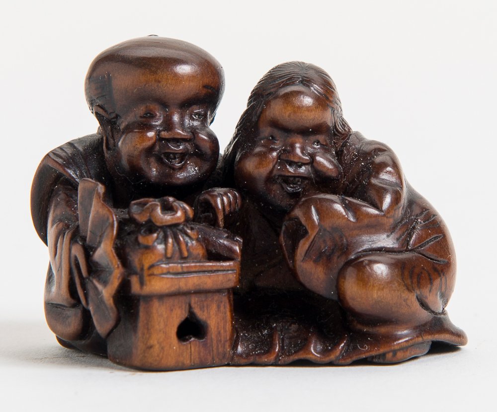 LUCKY DWARF FUKUSUKE WITH OKAME: Netsuke, Wood. Japan, 19th cent. Very well-crafted netsuke, presenting the two with their unmistakable heads close together. Lusty Okame (also Uzume) with fat cheeks and pear-shaped head, the lucky dw