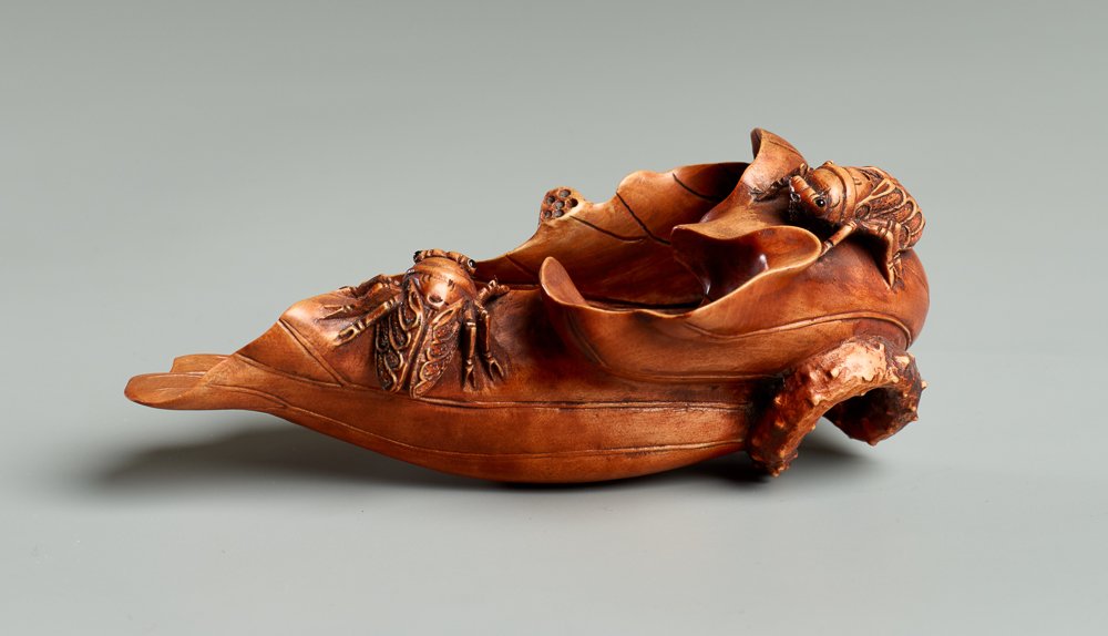 MITSUYUKI: LOTUS LEAF AND BEETLE: Okimono, tsuge wood. Japan, 19th cent. A masterfully crafted okimono in yellow-red boxwood. The lotus leaf and snake-like curved stem are curled inward nearly forming a cup, possibly meant as a tray. 