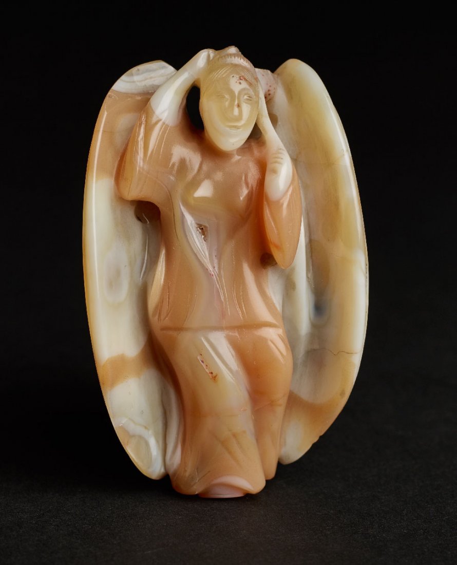 A FINELY HUED AGATE FIGURINE OF A FEMALE BUTTERFLY: Agate. China, 20th cent. CHINA, 20th cent. Clad in a floor-long robe, with two large wings. The reverse offering concentrical ribs. Provenance: German private collection. Height 6,5 cm Height 6,5 cm P