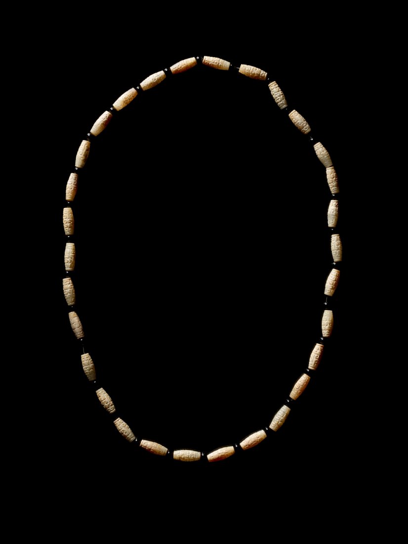 A GROUP OF 20 SIMILARLY-SHAPED BEADS ASSEMBLED INTO A: Jade. China, 4th - 3rd cent. BC Beads with a ‘barrel-shaped’ outline, such as those presented here, are attested in tombs dating from the middle of the Western Zhou period (10th century BC