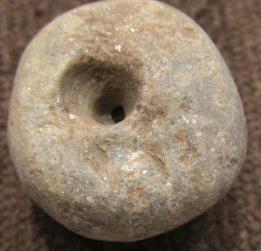 Pre-Columbian Stone Circular/Bead Object: By 1958, the owner remembers this in the family home. From 500-1500 years old, likely Mexican, stone with reflective surface, drilled in center resembling a large bead, 3/4" diameter and 1/2" thick.