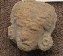 Pre-Columbian Clay Female Head Fragment: By 1958, the owner remembers this in the family home. From 500-1500 years old, likely Mexican, clay figure of a woman? With stylized hair, headdress, pierced ears, and some sort of line of braided hai