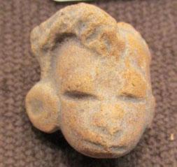 Pre-Columbian Clay Head Fragment: By 1958, the owner remembers this in the family home. From 500-1500 years old, likely Mexican, clay figure of a human, with left side large ear treatment and coiled hair across the forehead, the