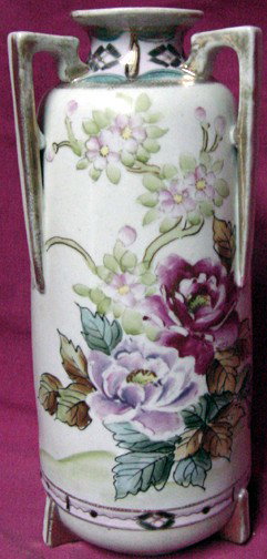 A Nippon Hand Painted Vase: Art Deco era handles and feet, floral designs, gold dotted trims, Nippon marking on base, 9 1/2" tall by 4" wide across the bottom.