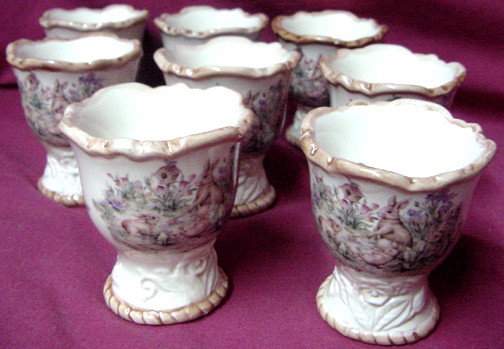 A Set 8 Ironstone Decorated Egg Cups: 1900-1920 era, set of 8, butterfly interiors, floral w/rabbits playing exteriors, about 2 1/2" tall and wide, unmarked. You are bidding on a set of 8 that are in excellent condition.