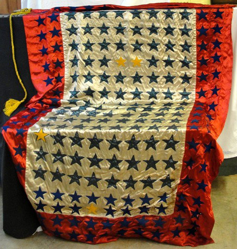 A Red White & Blue Patriotic Flag Handmade: Probably 1920s or 30s, handmade, satin and felt, satin blue outer border with blue felt stars, blue stars in center on white background, 3 mustard yellow stars, 5 feet tall by 7 feet long, moth damage