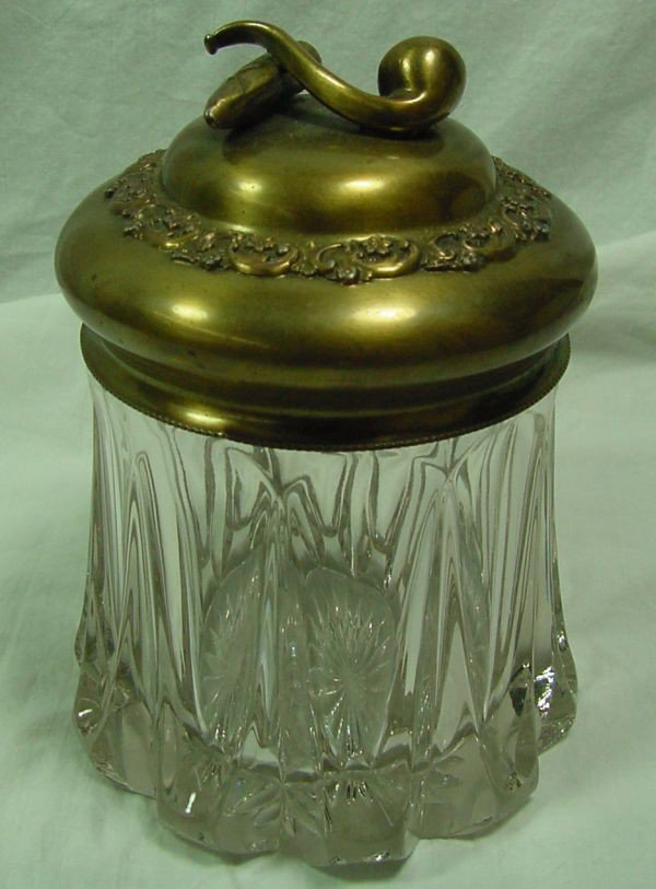 A Vintage Glass Humidor: 1900-1920 era, pipe and cigar finial, V shaped panels on the side of the glass almost making this into a prismatic look, mint condition, 6 1/2" tall to the top of the finial by 4 1/2" wide. This could