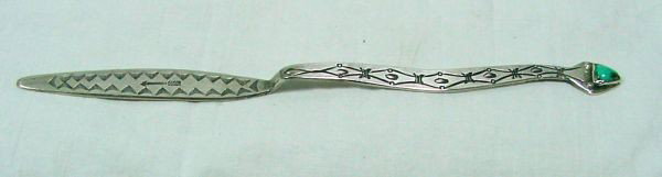 A Native American Silver & Turquoise Letter Opener: Probably 1920s era, unsigned, handmade silver letter opener, almost triangular shaped bezel set turquoise stone, there is an arrow with feathers in the center of the opener, heavily decorated on the f