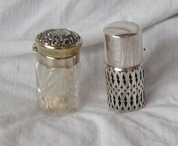 A Sterling Dresser Bottle Powder & Perfume: Ground glass stoppers, one covered in lattice work over dark green glass, screw off lid in silver and removable large green stopper, second is sterling hinged lid cut glass base with interior stopper 