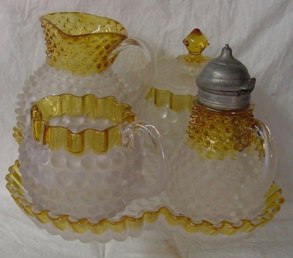 A Frances Ware Hobbs Table Set: Amber borders, shaped tray with dimensions of 10" wide by 1 1/2" tall, a covered syrup with pewter top, a milk pitcher, covered sugar and open creamer, minor nicks to some of the extremities but overa