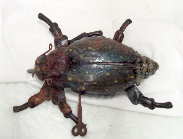 Beetle Tin Wind Up Friction Toy: Unusual size, 6" long by 5" wide by 2" tall to the top of the back, painted tin surface, wind up mechanism, probable replaced front wheel under the beetle's mouth, when wound up with the side key, the