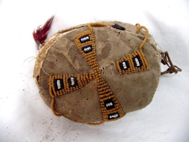 American Western Indian Fetish: 1880-1910 era, Western Indian, Beaded leather with red feathers hanging from one end, front and back sides have corn colored beads forming a cross with navy blue and center white beads.3 1/2" by 3", 1