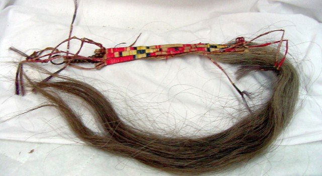 1880 Western Indian Beaded Artifact: 1880-1910 era, Western Indian, tanned leather with red, yellow and blue bindings to resemble beads, brass beads on one with a circular hanger?, and what appears to be horse hair on the opposite end of