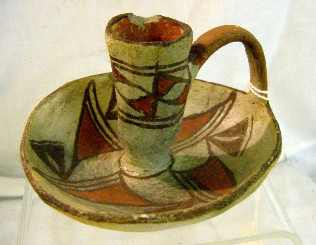 American Indian Western Pottery Candlestick: Unsigned, orange and white design, chipped upturned rim, handle intact, chipped edge around candle holder, 4" wide by 2 1/2" tall. 1950s.