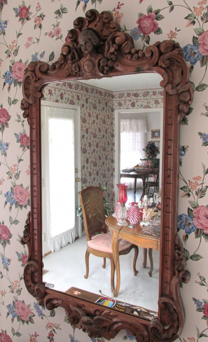 Mahogany 1920s Carved Mirror W/Face: Seemingly hand carved, ornate scrolling on the top with a childs head carved in the center of the crest, old wavy bubbly glass mirror, well carved bird in the center of the bottom of the frame. Mahoga