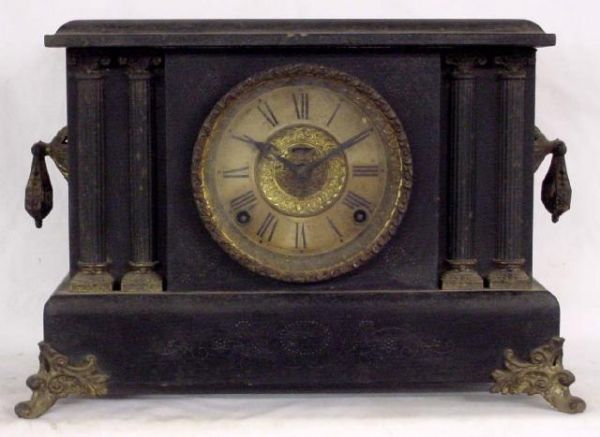 Ingraham Wooden Cased Black Mantel Clock: Half Fluted Columns On Each Side Of The Face, Decorative Loupes Hanging From Ends, Ornate Feet, Floral Incised Case, This Clock Needs A Good Cleaning, 10 1/2 Tall by 15 Wide, About 100 Years Old