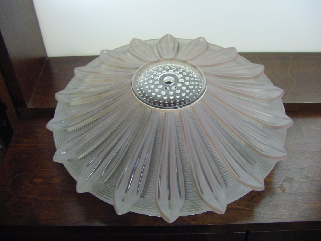 Ceiling Petal Shade: Ceiling fixture, 14" by 3 1/2" tall, clear glass, with a sort of petaled design, 4 nicks on the top of the teeth, center attachment, pale pink color in the glass.