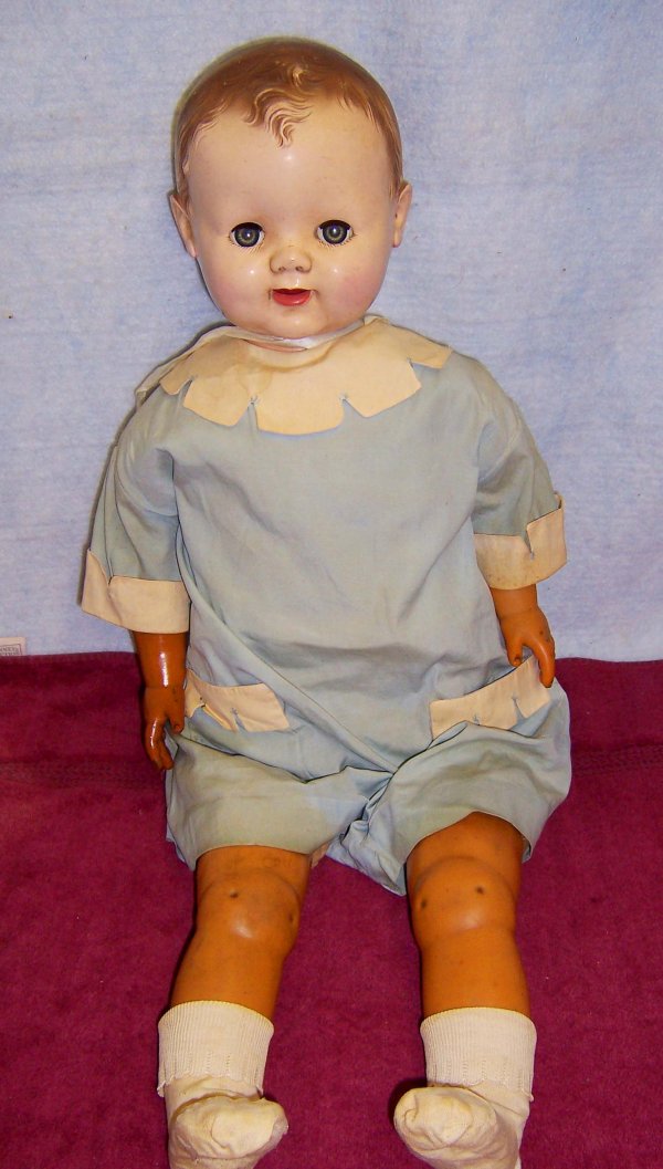 Effanbee cloth body baby doll: 26 in. tall hard plastic head with molded hair,vinyl arms and legs, sleep green eyes, open mouth showing 2 teeth on a cloth body with a record player in the torso. The face and description of the doll