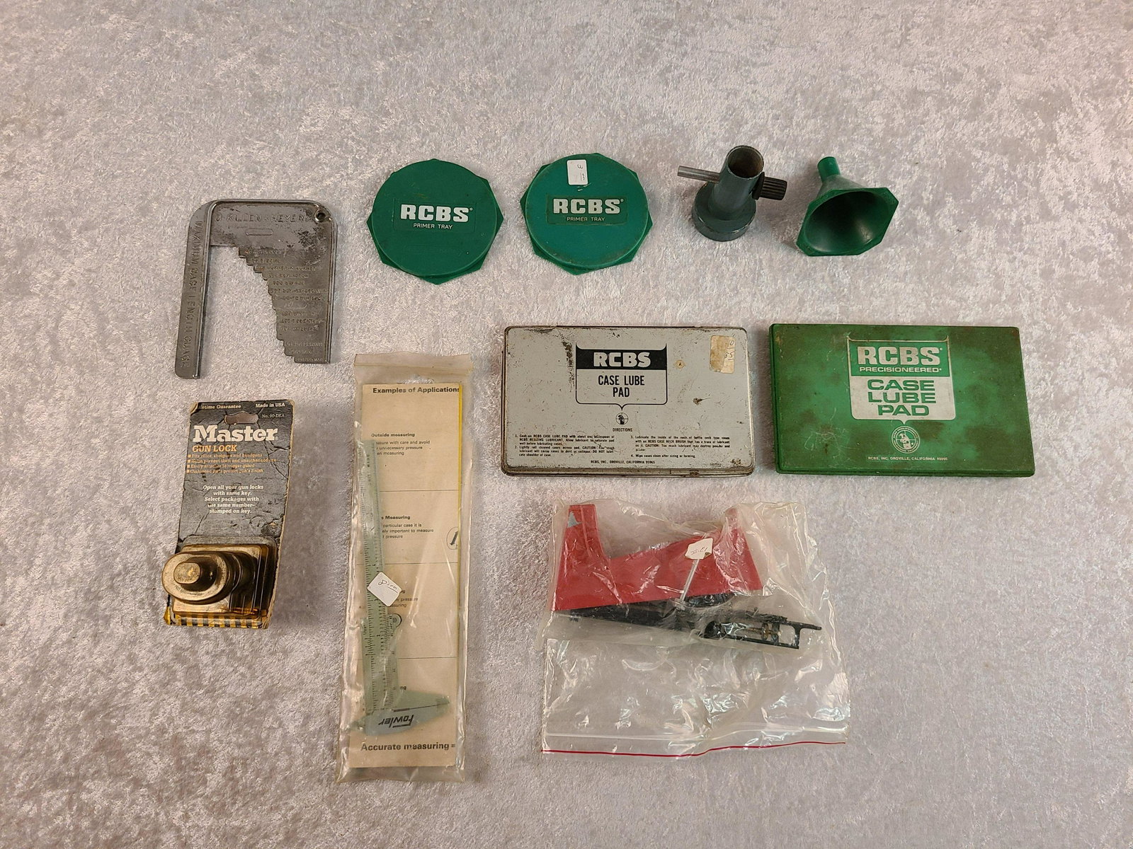 Box Lot of Reloading Equipment: Box Lot of Reloading Equipment: (2) RCBS Case Lube Pad, Powder Trickler, Case Length Gauge, Powder Funnel, Primer Trays, Fowler Calipers, Master Gun Lock, & Lee Powder Scale