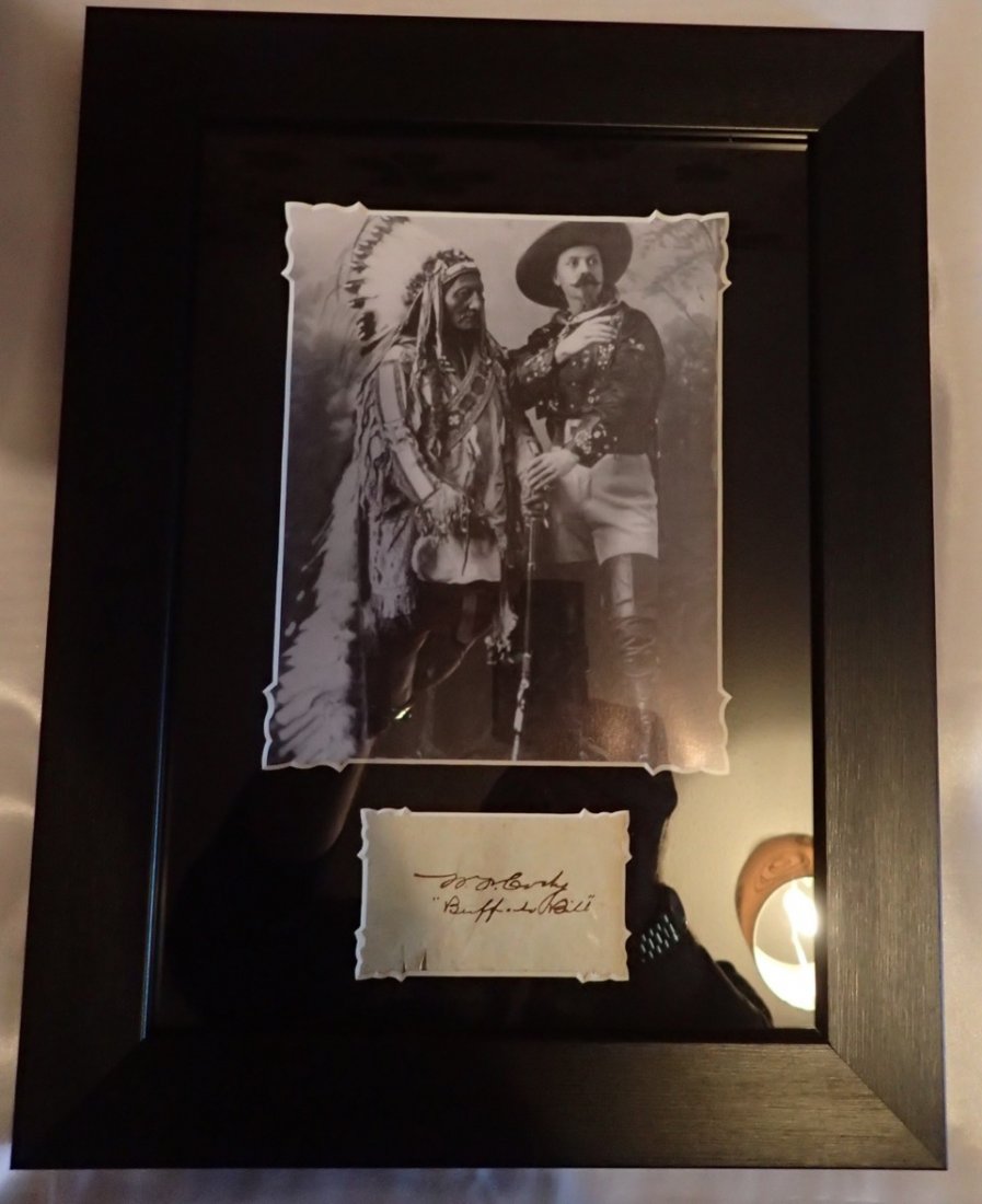 Buffalo Bill.: A cut leaf measuring 8 1/2 cm by 5 cm in size bearing the signature of William Frederick Cody AKA Buffalo Bill mounted with an image and framed at 38 1/2 cm by 29 1/2 cm in size in black and silver tr