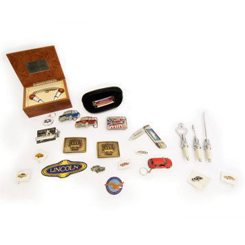 Automotive Lifestyle Accessories: " Lot includes two Franklin Mint collector knives, spark plug bar tools, a Cadillac corkscrew and wine toppers in a solid wood box, badges, pins, and an assortment of pewter and brass belt buckles. "