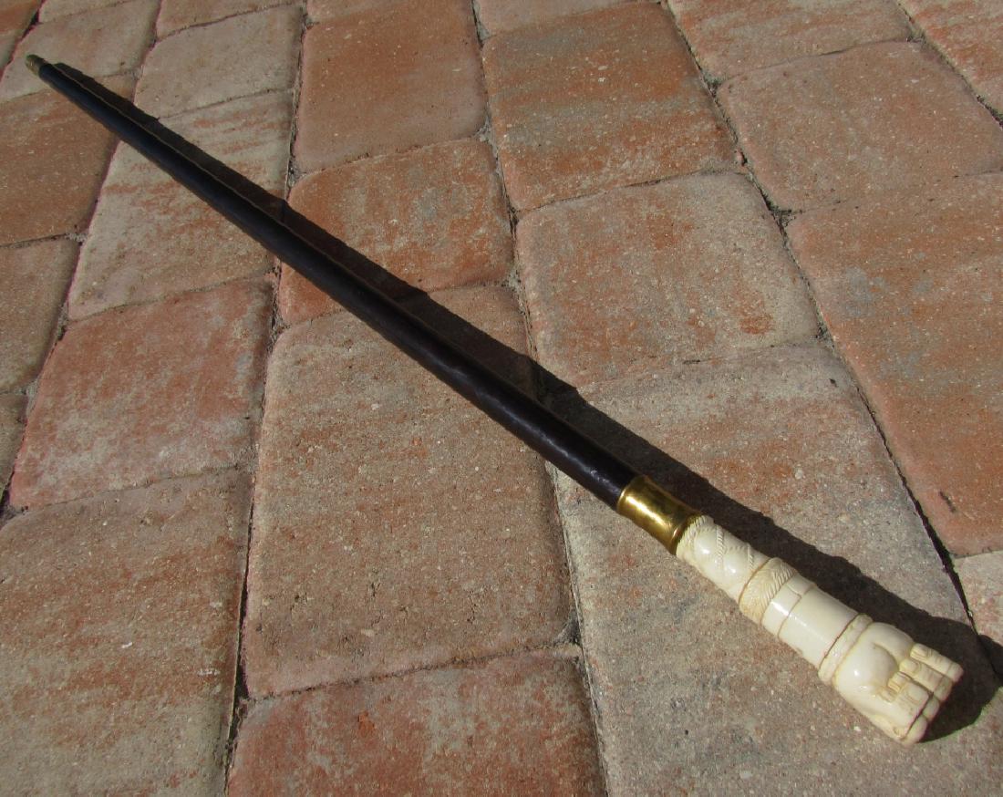 BONE FIST & SNAKE EBONY WOOD CANE WALKING STICK: ANTIQUE CARVED BONE HAND, BRASS, & EBONY WOOD WALKING CANE. 36.25" TALL. IMPORTANT: Bidding may not be accepted through LiveAuctioneers. Please contact us at ImperialAuctionCo.com to set up absentee o