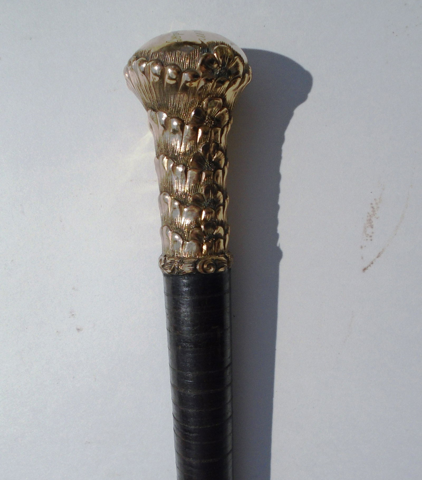 GOLD TOP PRESENTATION CANE STACKED LEATHER 1888: GOLD TOPPED WALKING STICK. TOP 1 1/2" WIDE, 2 7/8" TALL. 34 3/8" OVERALL. ENGRAVED "PRESENTED TO MOSSHEIM 57th BIRTHDAY 1888". (US SHIPPING $25)