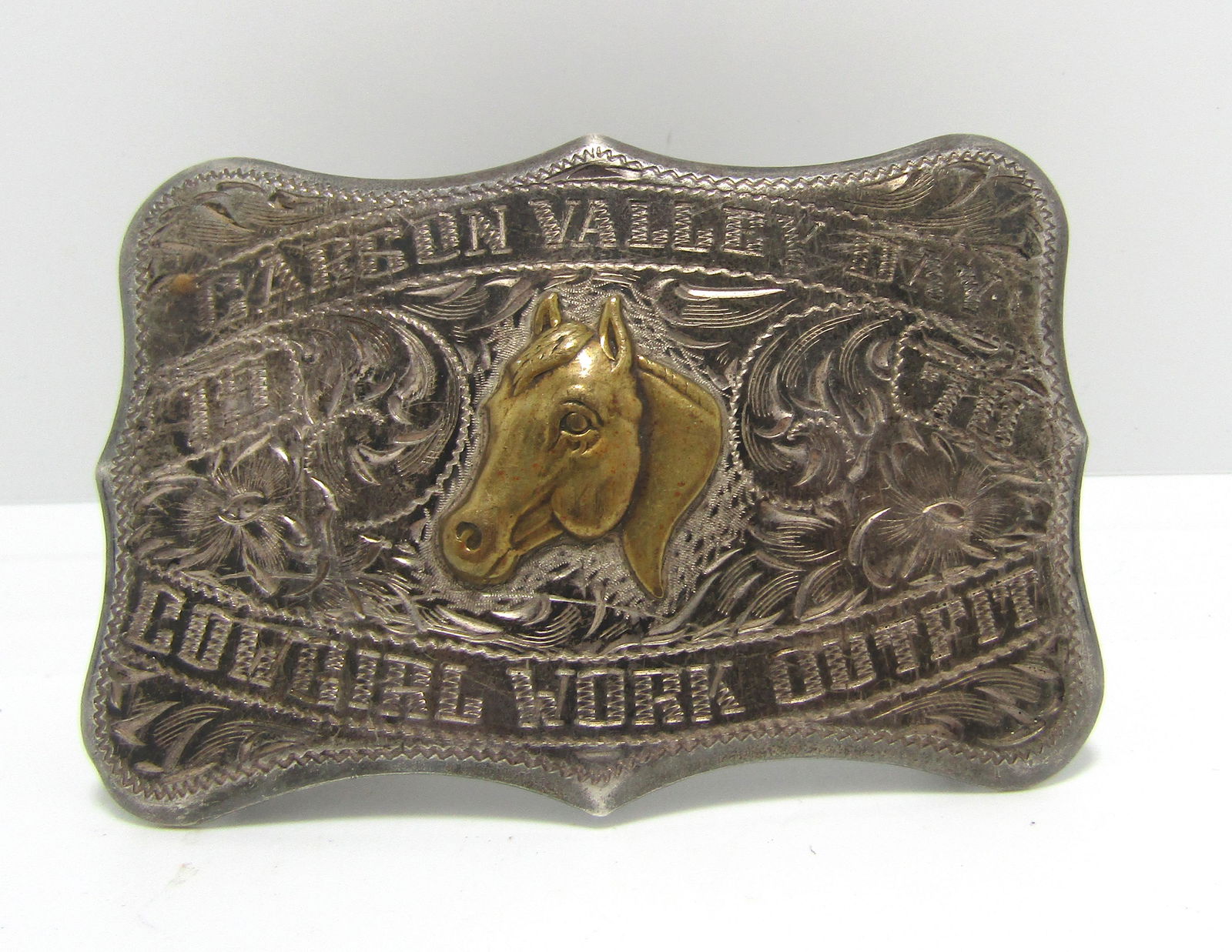 1970 CARSON DAY "COWGIRL WORK" STERLING BUCKLE: MARKED "1970 CARSON VALLEY DAY COWGIRL WORK OUTFIT". MARKED & TESTED STERLING SILVER. HAS BRASS HORSE HEAD ON FRONT. UNIQUE RODEO VINTAGE BELT BUCKLE, ALSO SIGNED DIABLO ON BACK. MEASURES 3" X 2". FIT