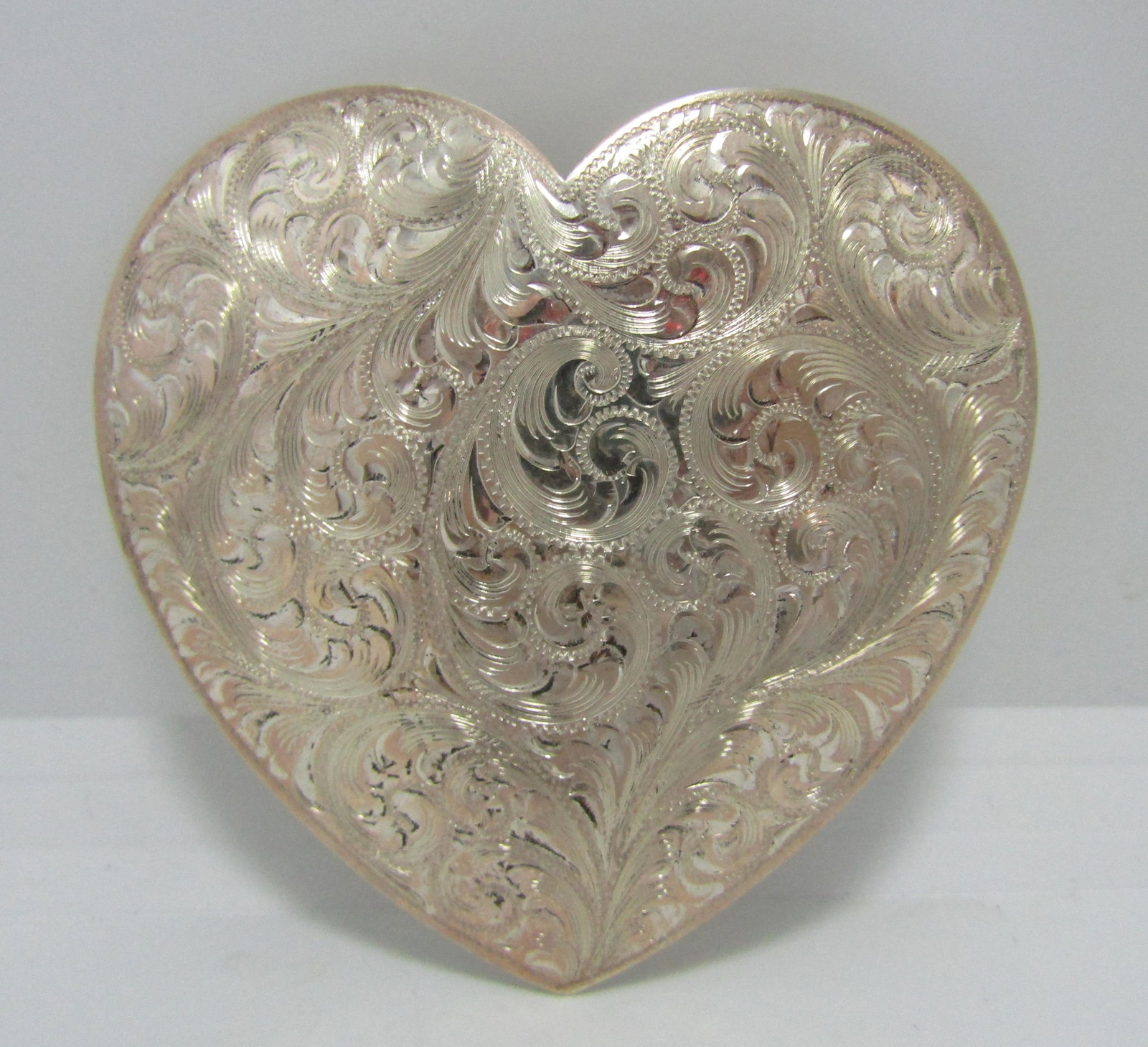 VTG WADE'S RENO NEVADA LARGE STERLING BELT BUCKLE: LARGE 3" SOUTHWESTERN HEART SHAPED BUCKLE. CHASED SCROLLWORK DESIGN. MARKED "RENO WADE'S SILVER SHOP STERLING" TESTED STERLING SILVER. MEASURES 3" X 3" AND FITS A 1.5" WIDE BELT. WEIGHS 60 GRAMS. USA 
