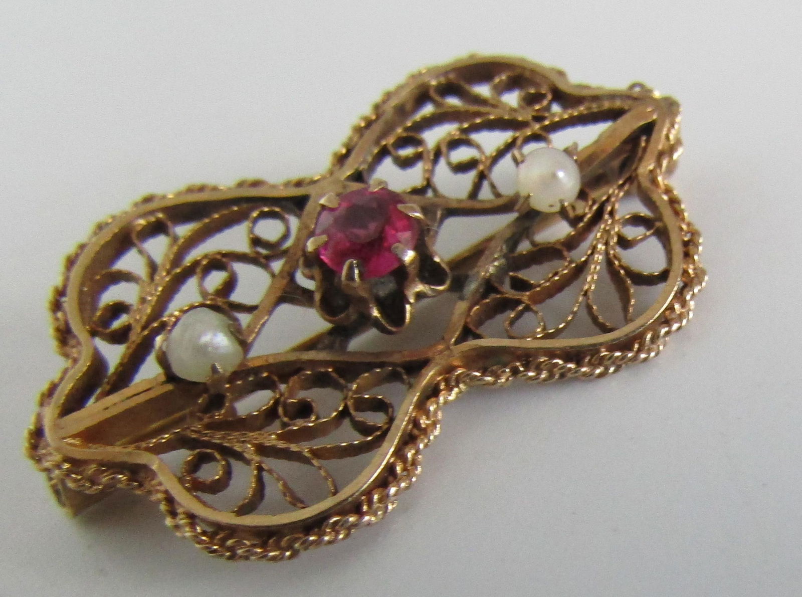 RUBY PEARL PIN FILIGREE BROOCH 10K GOLD: ANTIQUE MARKED AND TESTED "10K OB" MEASURES 25MM BY 15MM. 10 POINT RUBY RED STONE AND 2 NATURAL PEARLS. EXCELLENT CONDITION. WEIGHS 2GRAMS. THE SLIP PIN LOCK WORKS FINE. USA SHIPPING $5.