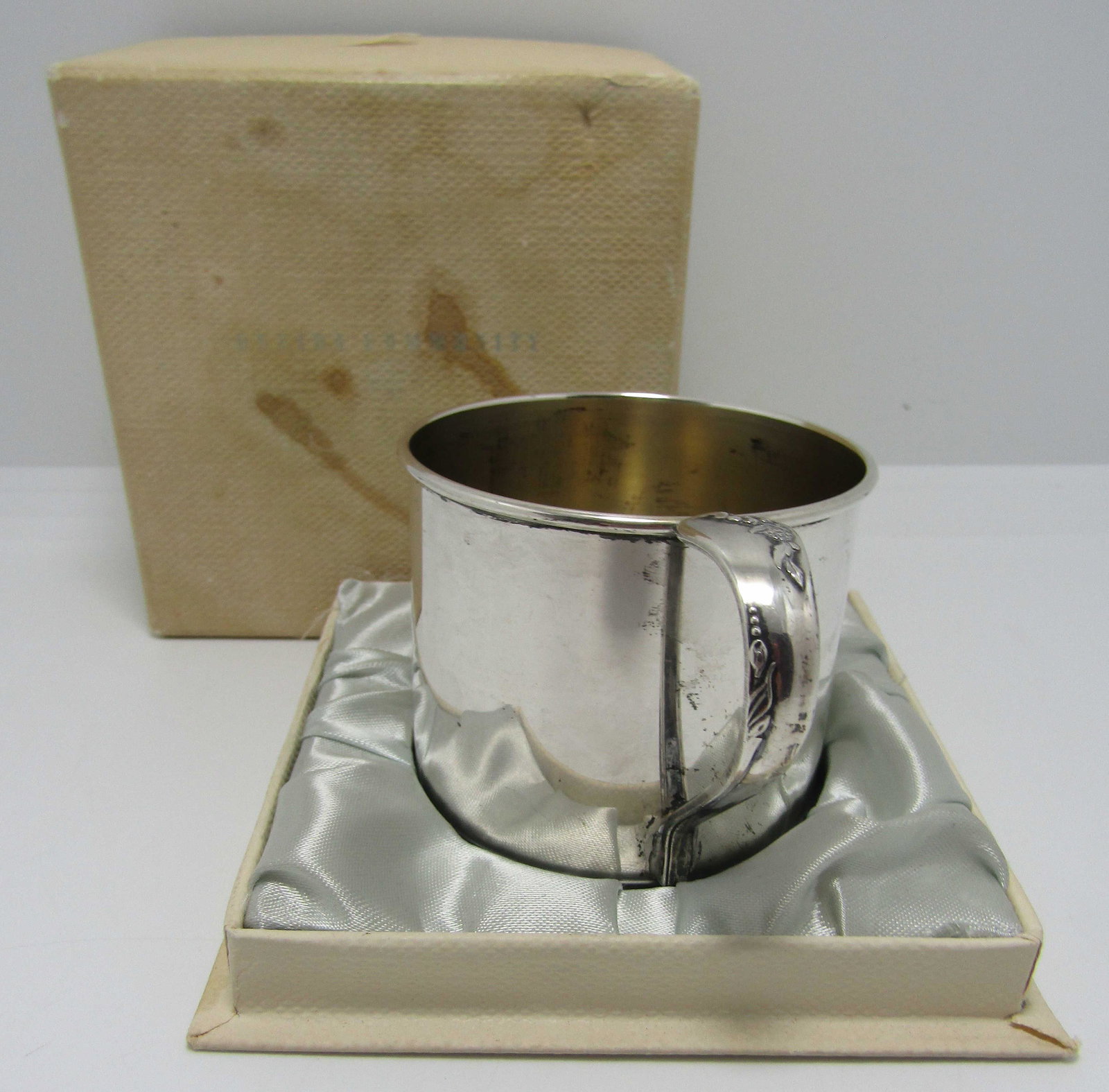 ONEIDA COMMUNITY STERLING SILVER ENGAGEMENT CUP: NEW IN BOX, OLD OLD STOCK BABY CUP. MEASURES 2 INCHES TALL BY 2.25 INCHES WIDE, 3.5 INCHES WITH HANDLE. WEIGHS 56.2 GRAMS. CUP WAS NEVER USED. NO MONOGRAM. EXCELLENT CONDITION. THE ORIGINAL BOX IS STA