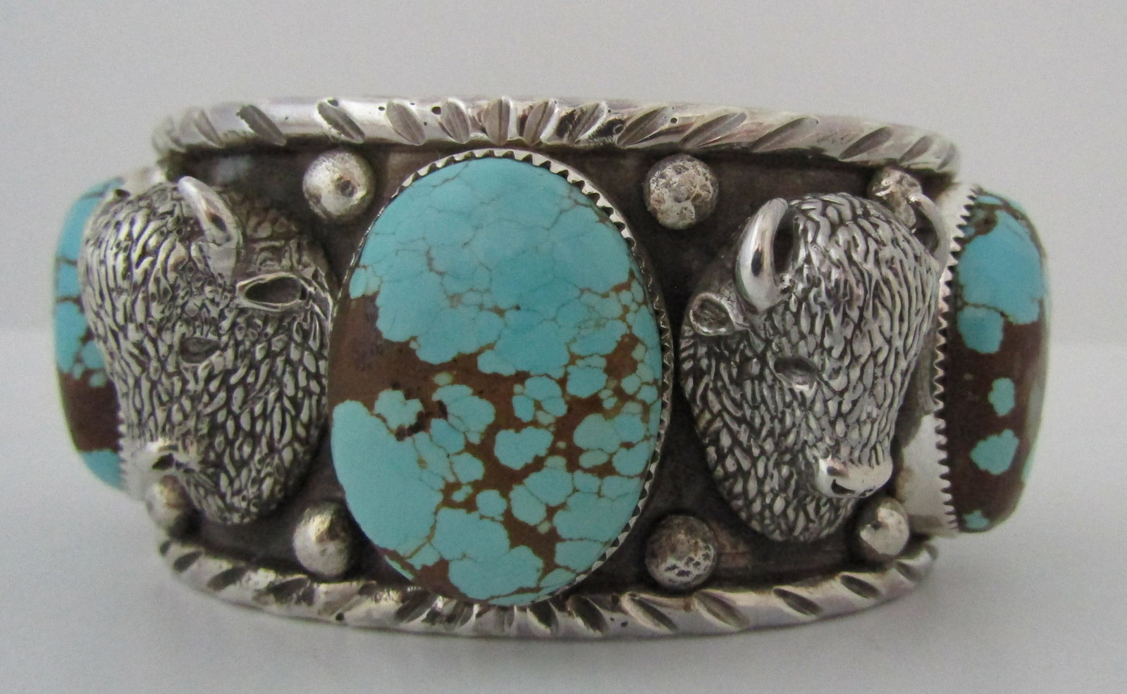 SAN FELIPE #8 TURQUOISE BUFFALO CUFF BRACELET: STERLING SILVER CUFF BRACELET SET WITH NUMBER 8 TURQUOISE . HAS 4 RAISED BUFFALO HEADS. 1 1/2 INCH WIDE AND FITS FITS 7 1/2 WRIST WITH 1 5/8 INCH OPENING. WEIGHS 169 GRAMS. ALL SIGNED SAN FELIPE JOCOB