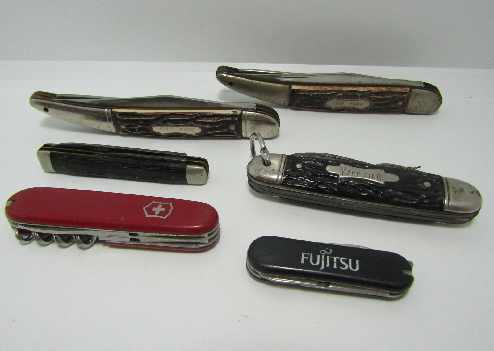 LOT OF 6 VINTAGE FOLDING POCKET KNIVES IMPERIAL: ONE VICTORINOX SWISS ARMY KNIFE, TWO 9" COLONIAL FISH KNIVES (ONE SHARPENED DOWN 1/2"), ONE IMPERIAL KAMP KING FOLDER, ONE FUJITSU, ONE UNMARKED. NO BLADES BROKEN, VINTAGE CONDITION, COULD USE CLEANIN