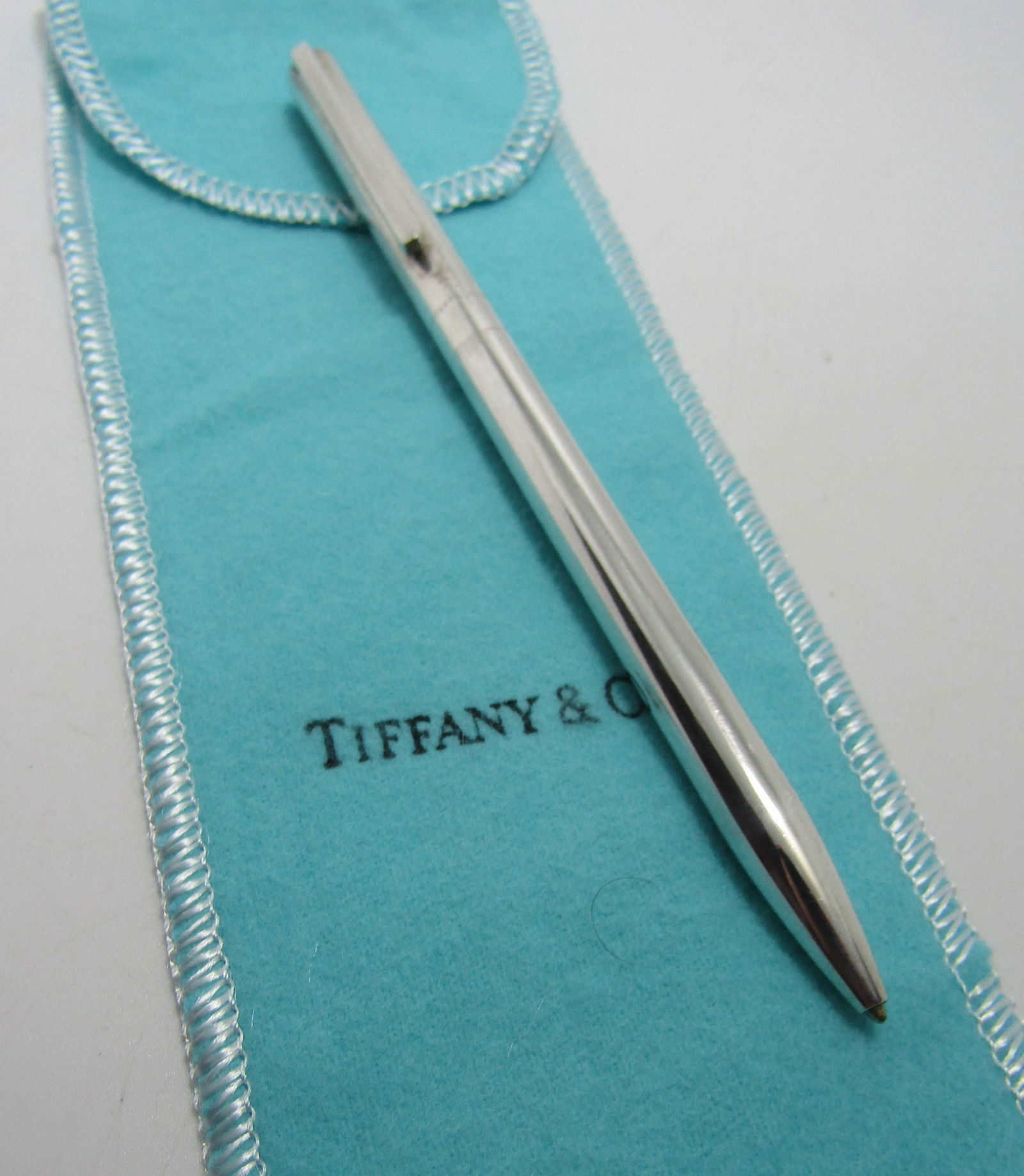 TIFFANY & CO BLUE INK PEN STERLING SILVER W POUCH: GENUINE SIGNED "TIFFANY & CO 925 USA". MEASURES 5 1/4 INCHES LONG. WEIGHS 25 GRAMS. BLUE INK. EXCELLENT USED CONDITION. WITH TIFFANY POUCH. USA SHIPPING $5.