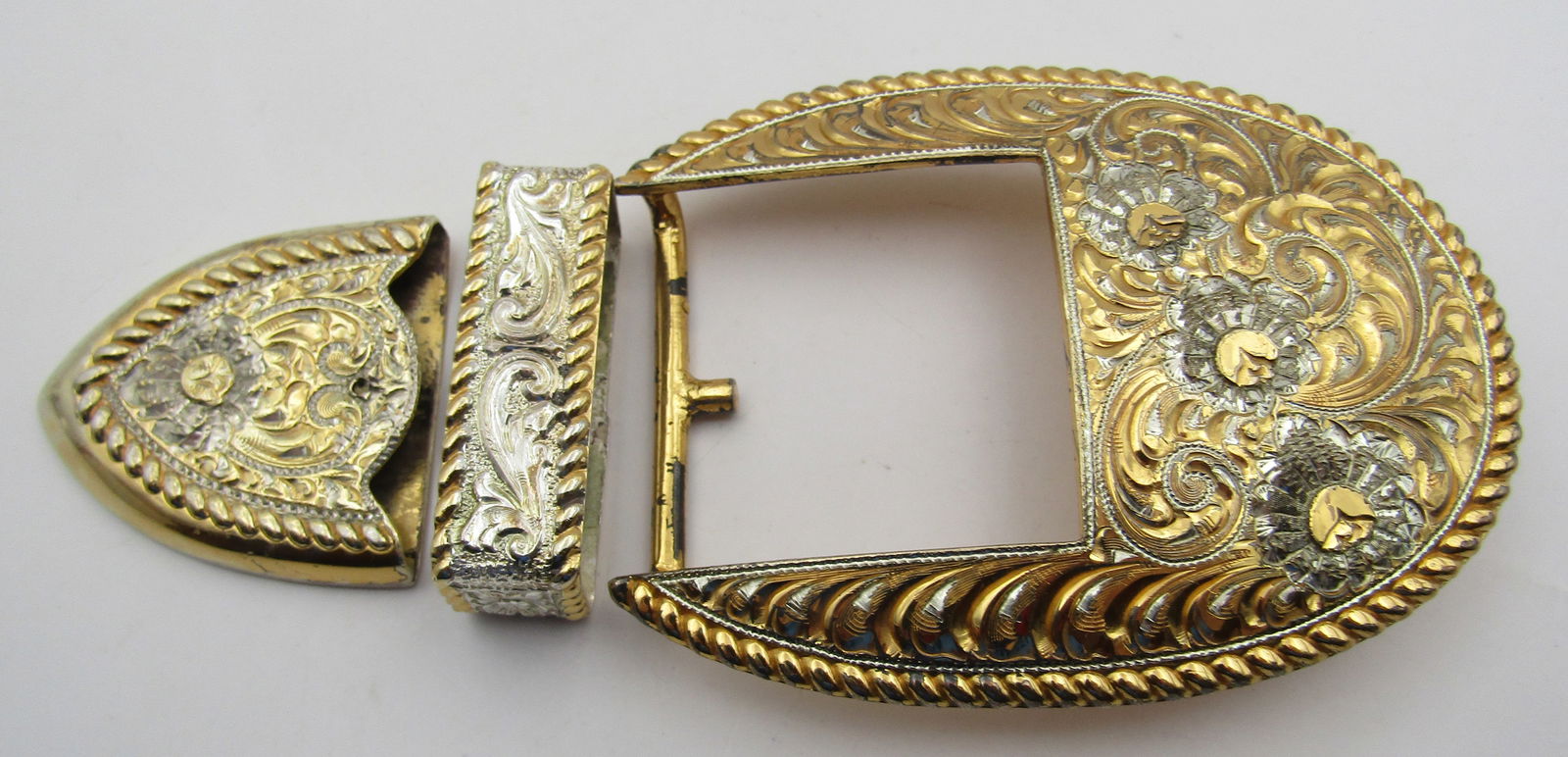 98GR CRUMRINE BELT BUCKLE 22K GOLD/STERLING SILVER: VINTAGE ESTATE 3 PIECE RANGER BUCKLE SET MARKED "CRUMRINE MFG RENO NV USA 22K GOLD ON STERLING" IN AN ORNATELY DETAILED BELT BUCKLE. MEASURES 3 1/2 INCHES BY 2 1/2 INCHES. WEIGHS 98.8 GRAMS. EXCELLENT