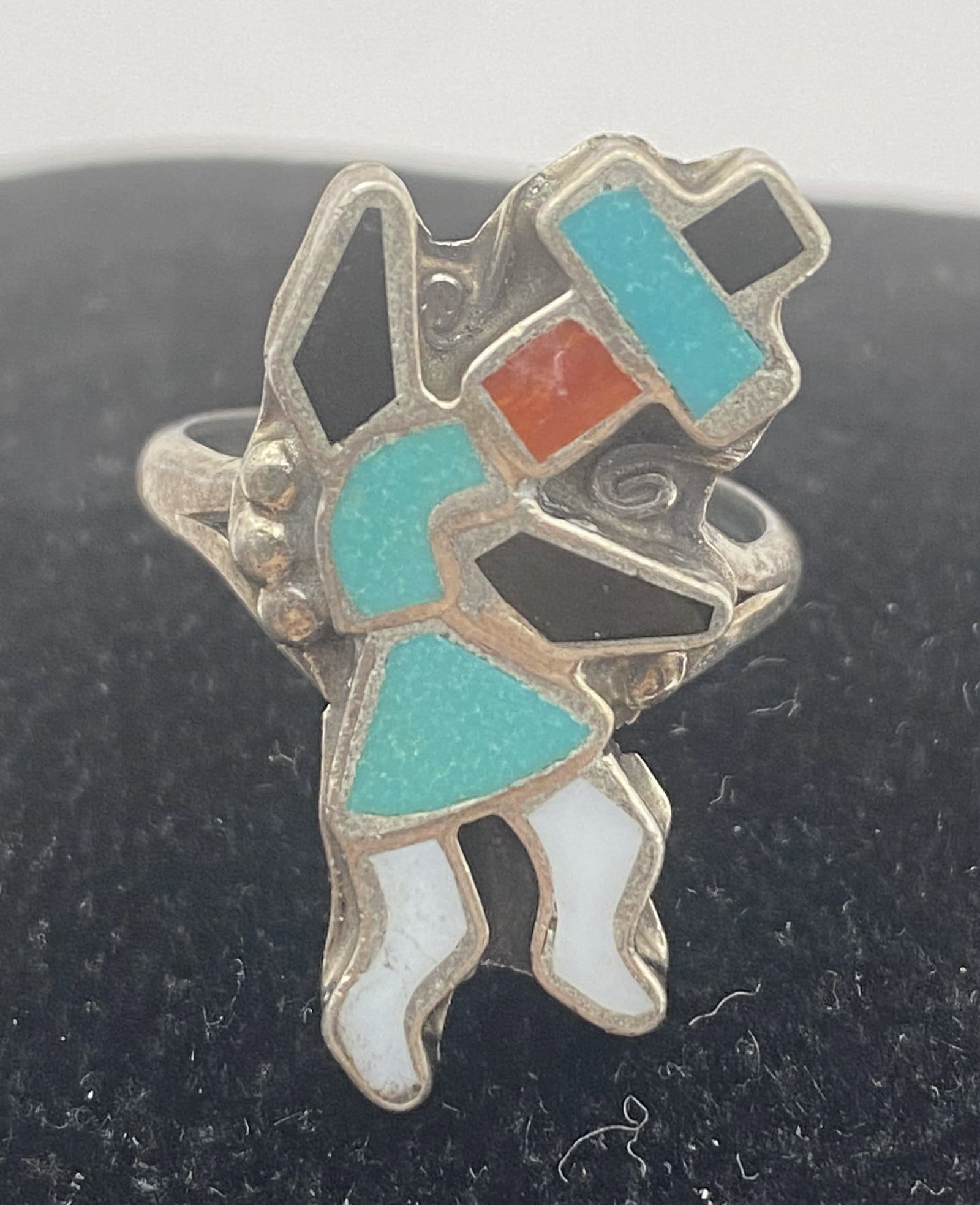 STERLING ZUNI CORAL TURQUOISE KACHINA RING: NATIVE AMERICAN HANDMADE KACHINA DANCER RING. MULTICOLOR INLAID STONES SHELL ONYX RED CORAL AND TURQUOISE. UNMARKED UNSIGNED TESTED STERLING SILVER. WEIGHS 4.2 GRAMS. KACHINA IS 1" TALL. WITH IMPERIAL