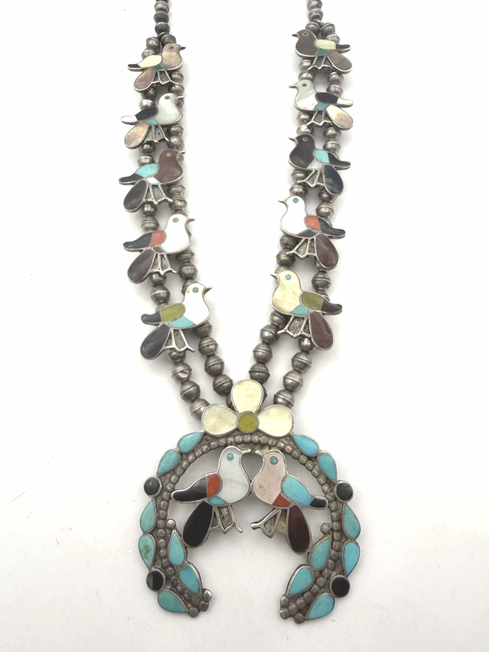 ELLA GIA STERLING BIRD SQUASH BLOSSOM NECKLACE: VINTAGE HANDMADE NATIVE AMERICAN SQUASH BLOSSOM NECKLACE. SIGNED BY ZUNI ARTISAN COUPLE WESLEY & ELLA L GIA ZUNI NEW MEX. TESTED STERLING SILVER WITH TURQUOISE ONYX MOTHER OF PEARL RED CORAL AND GASPE