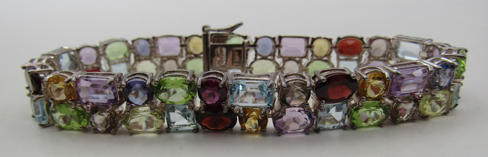 15CT ASSORTED STONE BRACELET STERLING SILVER 24GR: VINTAGE ESTATE ASSORTED COLORED STONES: AMETHYST, GARNET, PEARL, PERIDOT, BLUE TOPAZ, CITRINE & OTHERS. MEASURES 7.25 INCHES LONG BY .50". WEIGHS 24.6 GRAMS. EXCELLENT USED CONDITION. WITH