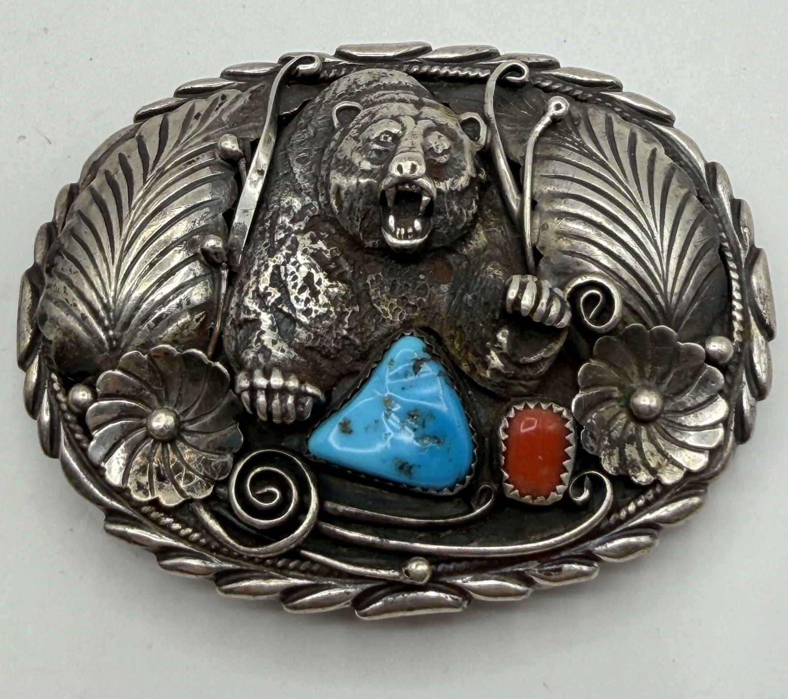 RICHARD BEGAY BEAR STERLING TURQUOISE BELT BUCKLE: NATIVE AMERICAN HANDMADE BELT BUCKLE. RED CORAL AND TURQUOISE STONES WITH A LARGE ROARING BEAR. MARKED SIGNED "RB" FOR RICHARD AND RITA BEGAY. TESTED STERLING SILVER. MEASURES JUST UNDER 3" LONG AND 2