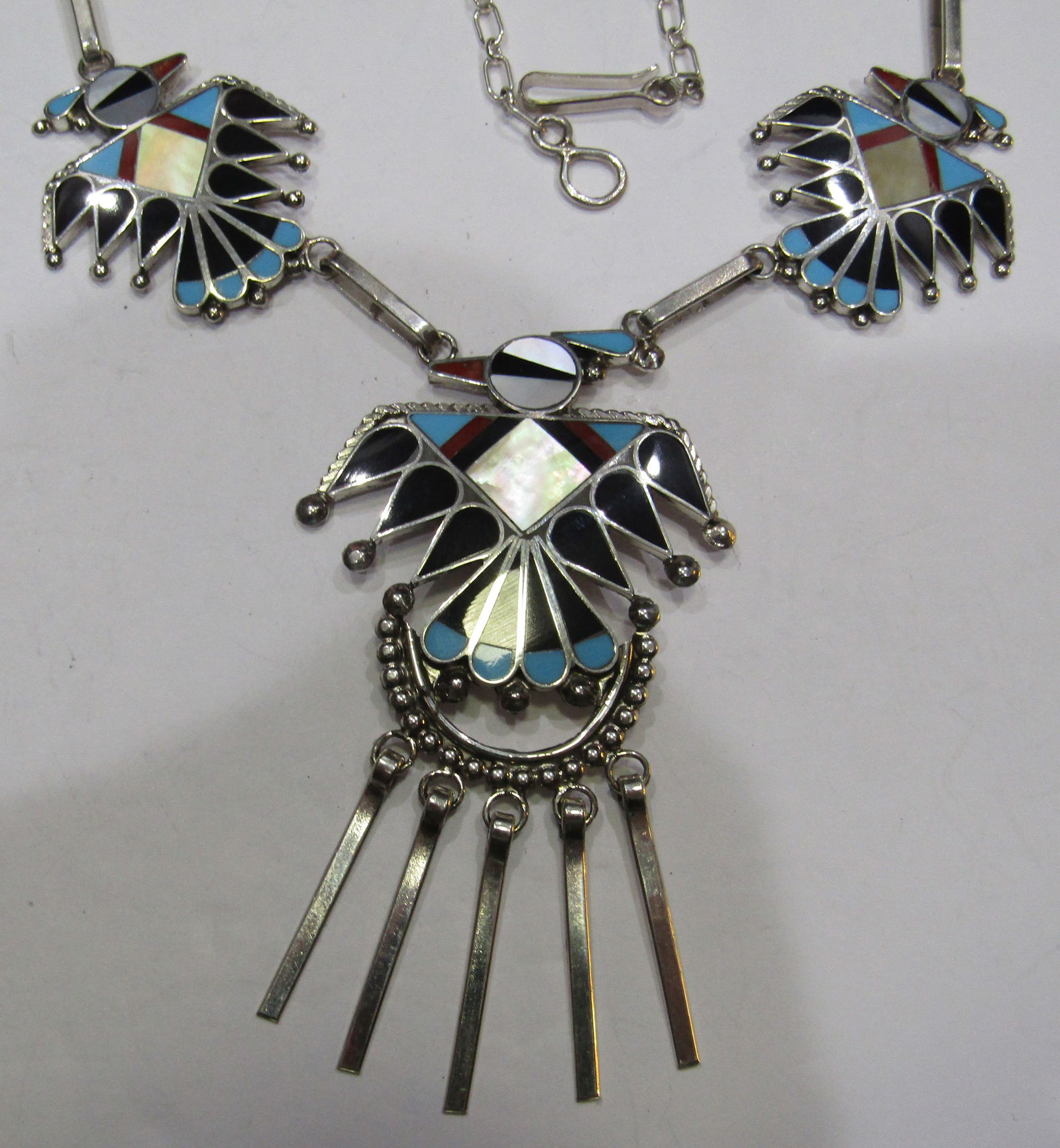 "WALLACE" TURQUOISE THUNDERBIRD NECKLACE STERLING: ARTIST SIGNED "AW ZUNI" ADRIAN WALLACE. 3 FABULOUS INLAID THUNDERBIRDS; TURQUOISE, JET, MOP & RED CORAL. MEASURES 19 INCHES LONG PLUS A 3 INCH CENTER BIRD DROP. TESTED STERLING SILVER. NATIVE AMERICAN