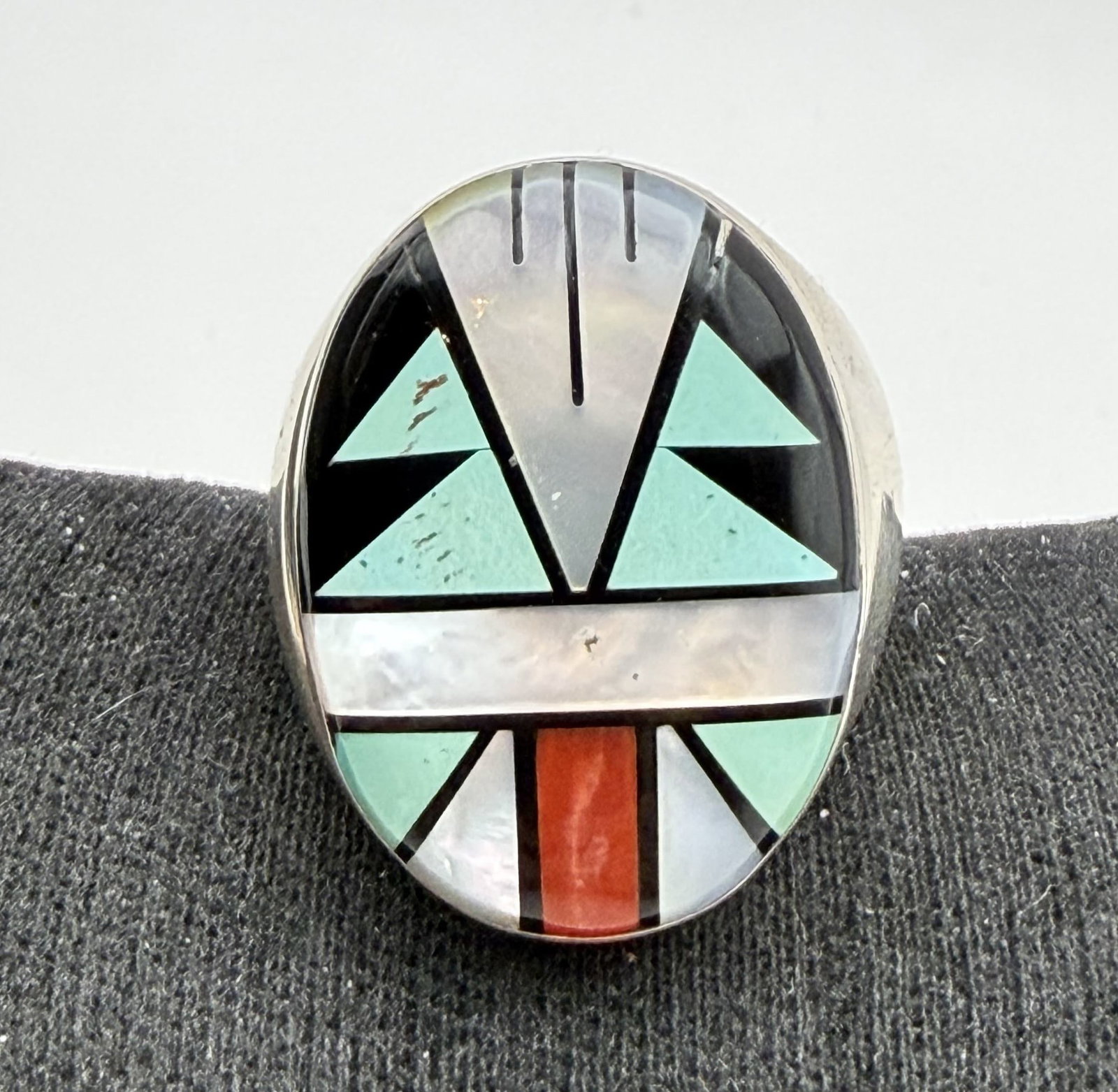 28g ZUNI STERLING TURQUOISE RED CORAL RING SIZE 11: ZUNI NATIVE AMERICAN INLAID SIZE 11 RING. RED CORAL ONYX TURQUOISE AND MOTHER OF PEARL SHELL STONES. MARKED TESTED STERLING SILVER. FACE OF RING IS 1-1/8" NORTH SOUTH. WEIGHS 28.7 GRAMS TOTAL. WITH IM