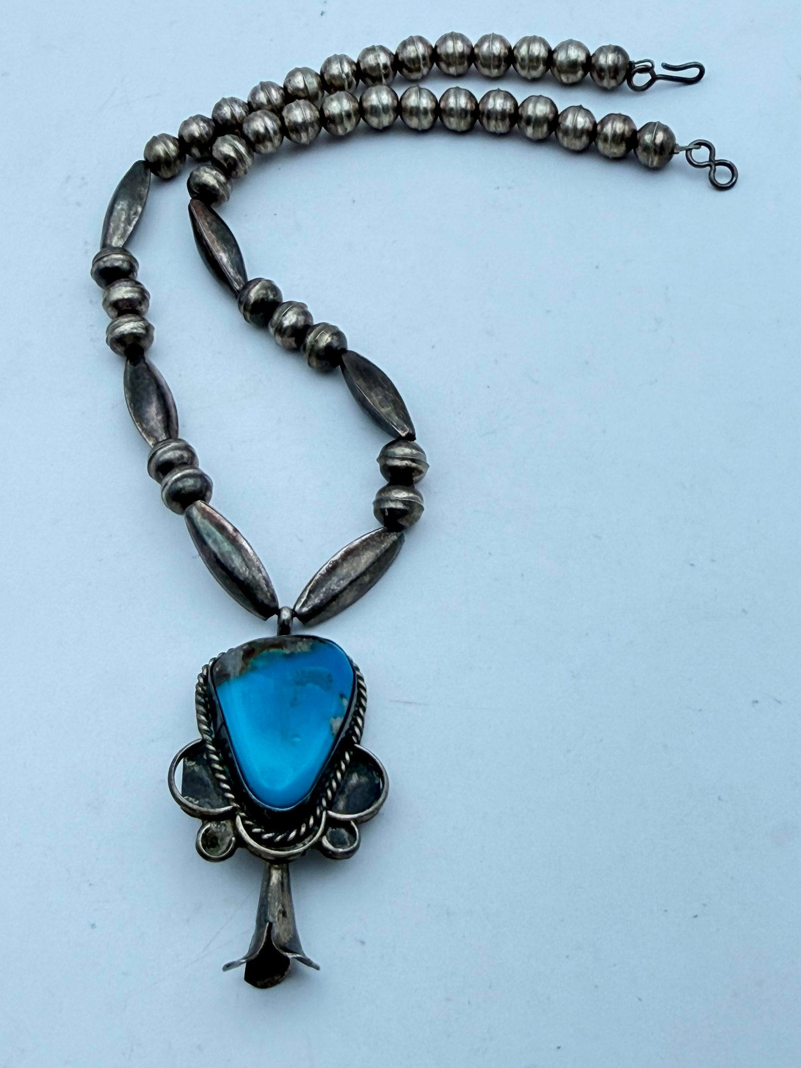 SQUASH BLOSSOM PENDANT NECKLACE STERLING NAVAJO: VINTAGE NATIVE AMERICAN NAVAJO HANDMADE BEADED TURQUOISE NECKLACE. UNMARKED UNSIGNED TESTED STERLING SILVER. MEASURES 15". 8MM SEAM BEADS. STONE HAS SOME SCRATCHES. CENTER PENDANT IS 1.75". WEIGHS 25 