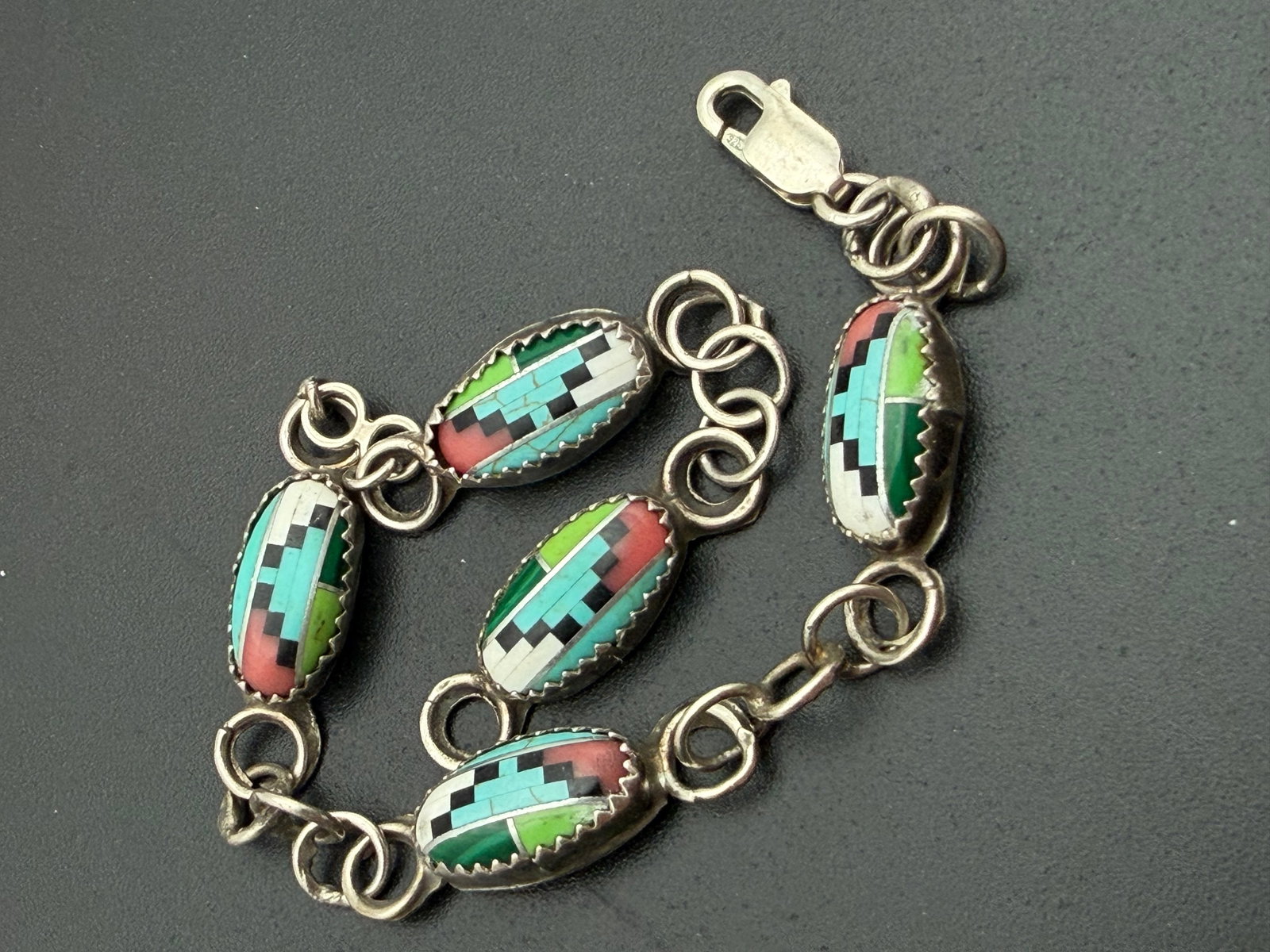 INLAID MULTICOLOR TURQUOISE STERLING BRACELET: NATIVE AMERICAN HANDMADE LINK BRACELET. MULTICOLOR BLOCK STONES. UNMARKED UNSIGNED TESTED STERLING SILVER. MEASURES 7.5" X 0.25". WEIGHS 8.6 GRAMS. WITH IMPERIAL AUCTION THE COST FOR PACKING AND SHIPP