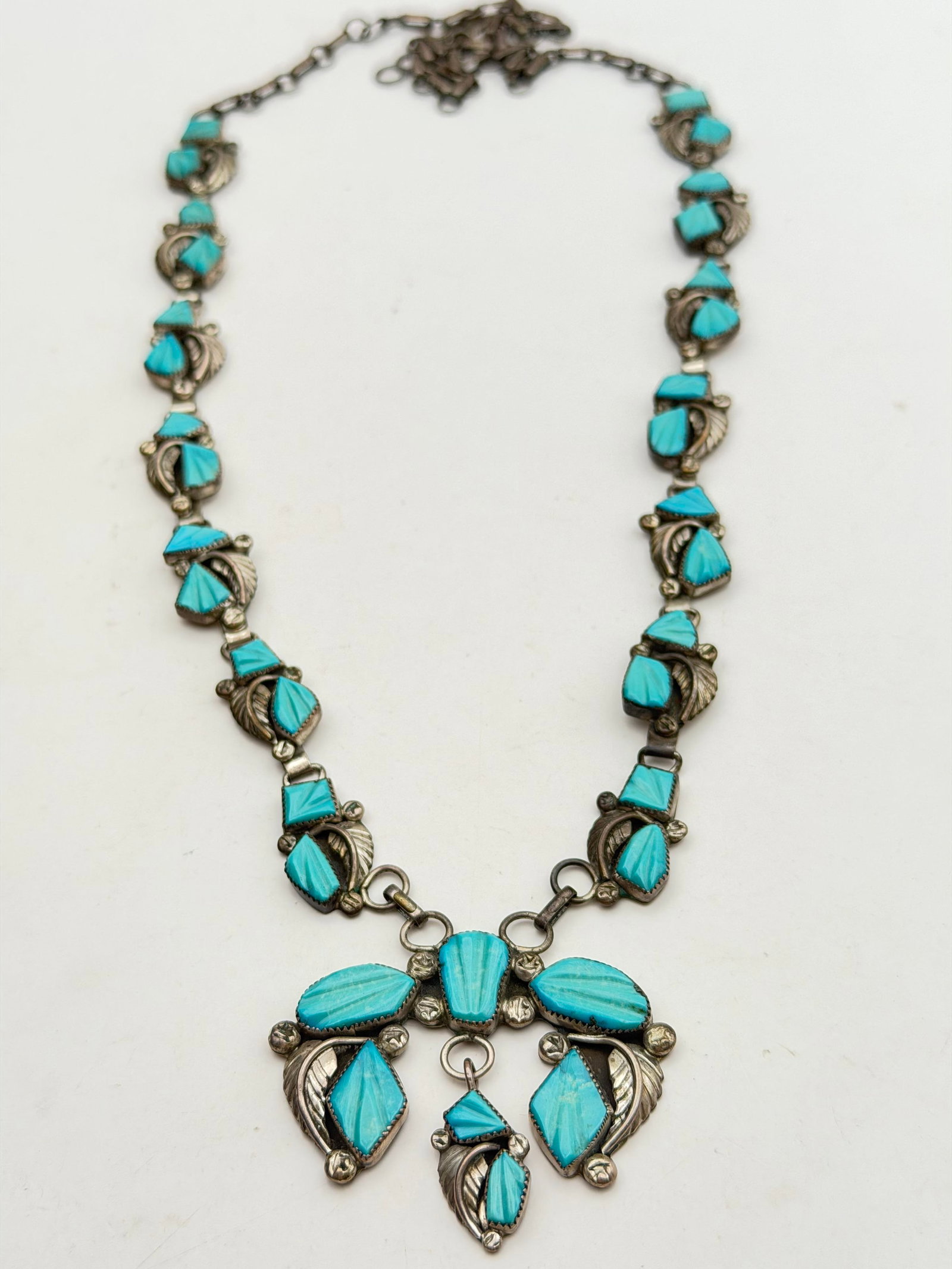 "CA" STERLING TURQUOISE SQUASH BLOSSOM NECKLACE: VINTAGE SIGNED "CA" NATIVE AMERICAN SQUASH BLOSSOM NECKLACE. TURQUOISE STONES ARE CARVED WITH CHANNELS TO PRODUCE A UNIQUE FLORAL DESIGN. TESTED STERLING SILVER. NECKLACE IS 27". CENTER NAJA PENDANT I