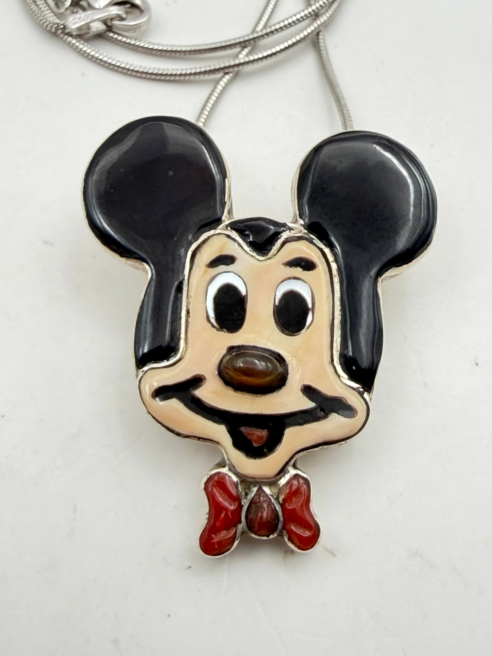 MICKEY MOUSE ZUNI STERLING PENDANT NECKLACE PIN: NEW OLD STOCK NATIVE AMERICAN HANDMADE PIN PENDANT. ZUNITOON DISNEY CHARACTER MADE WITH INLAID ONYX, SHELL AND RED CORAL BOWTIE. SIGNED "AL" FOR ANDREA LONJOSE. MARKED TESTED STERLING SILVER. MEASURES