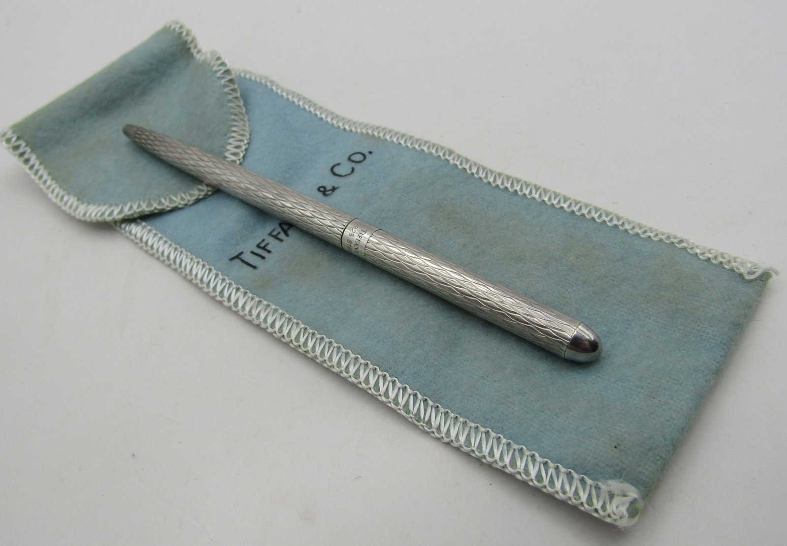 TIFFANY & CO STERLING SILVER PEN W POUCH: GENUINE SIGNED "TIFFANY & CO. STERLING" WITH POUCH. MEASURES 4.75 INCHES LONG. WEIGHS 13.5 GRAMS STERLING SILVER. EXCELLENT USED CONDITION; SMALL MONOGRAM BY MARK "MRS". NEEDS INK. WITH IMPERIAL AUCTI
