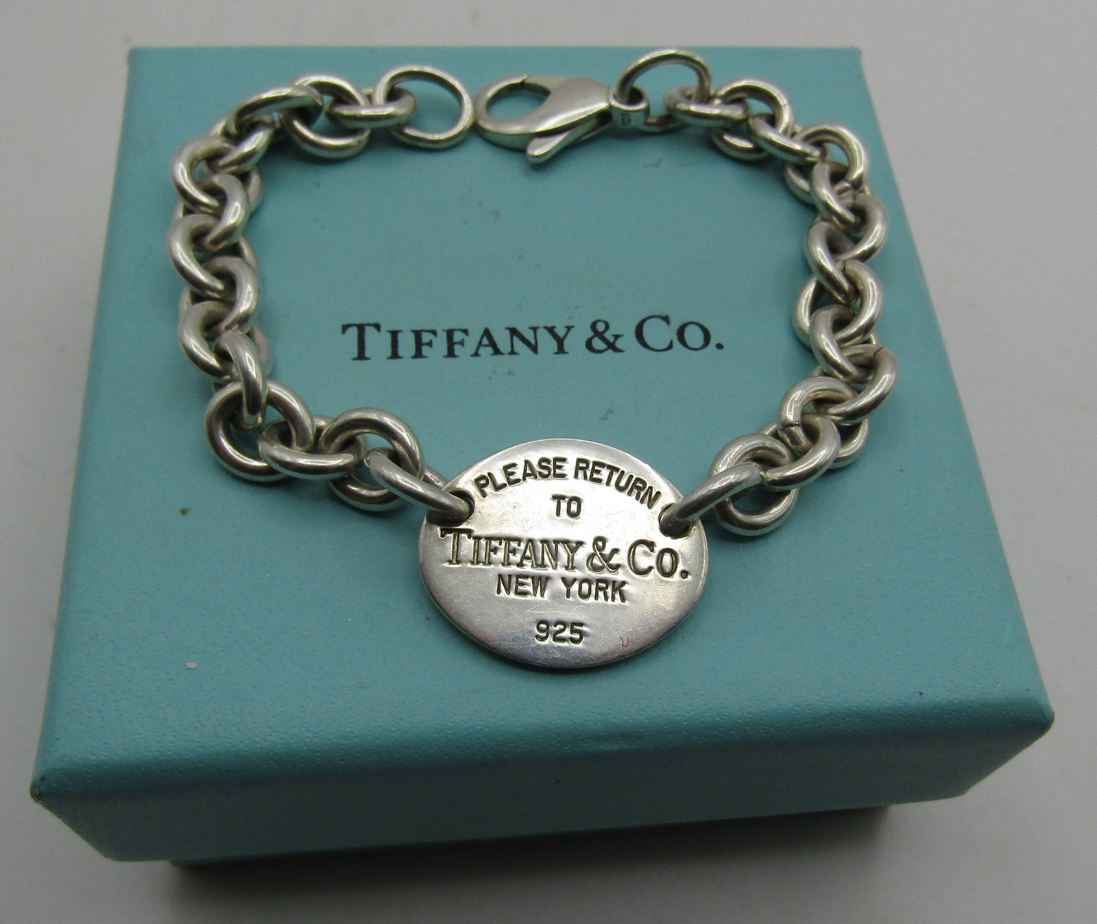 TIFFANY & CO BRACELET STERLING SILVER 27.7GRAMS: GENUINE SIGNED "PLEASE RETURN TO TIFFANY & CO. NEW YORK 925" WITH TIFFANY BOX. MEASURES 7.5 INCHES LONG. WEIGHS 27.7 GRAMS STERLING SILVER. EXCELLENT USED CONDITION. WITH IMPERIAL AUCTION THE COST FOR