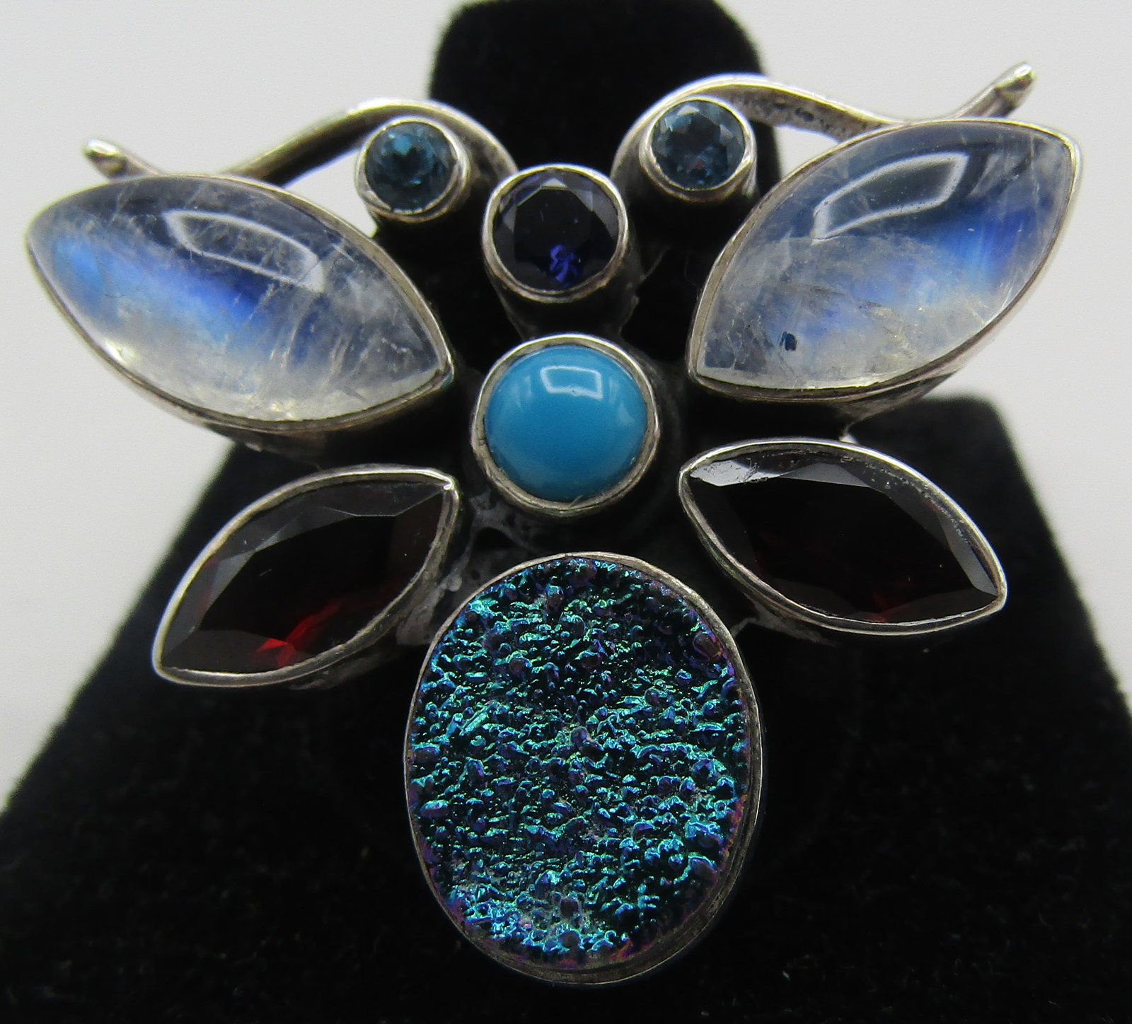 MULTIGEMSTONE BUTTERFLY RING STERLING SILVER 13GRM: SIZE 9. BUTTERFLY DESIGN WITH ASSORTED GEM STONES: DRUZY, GARNET, TURQUOISE, MOONSTONE, BLUE TOPAZ MOUNTED IN STERLING SILVER. WEIGHS 13.5 GRAMS. EXCELLENT CONDITION. WITH IMPERIAL AUCTION THE COST FO