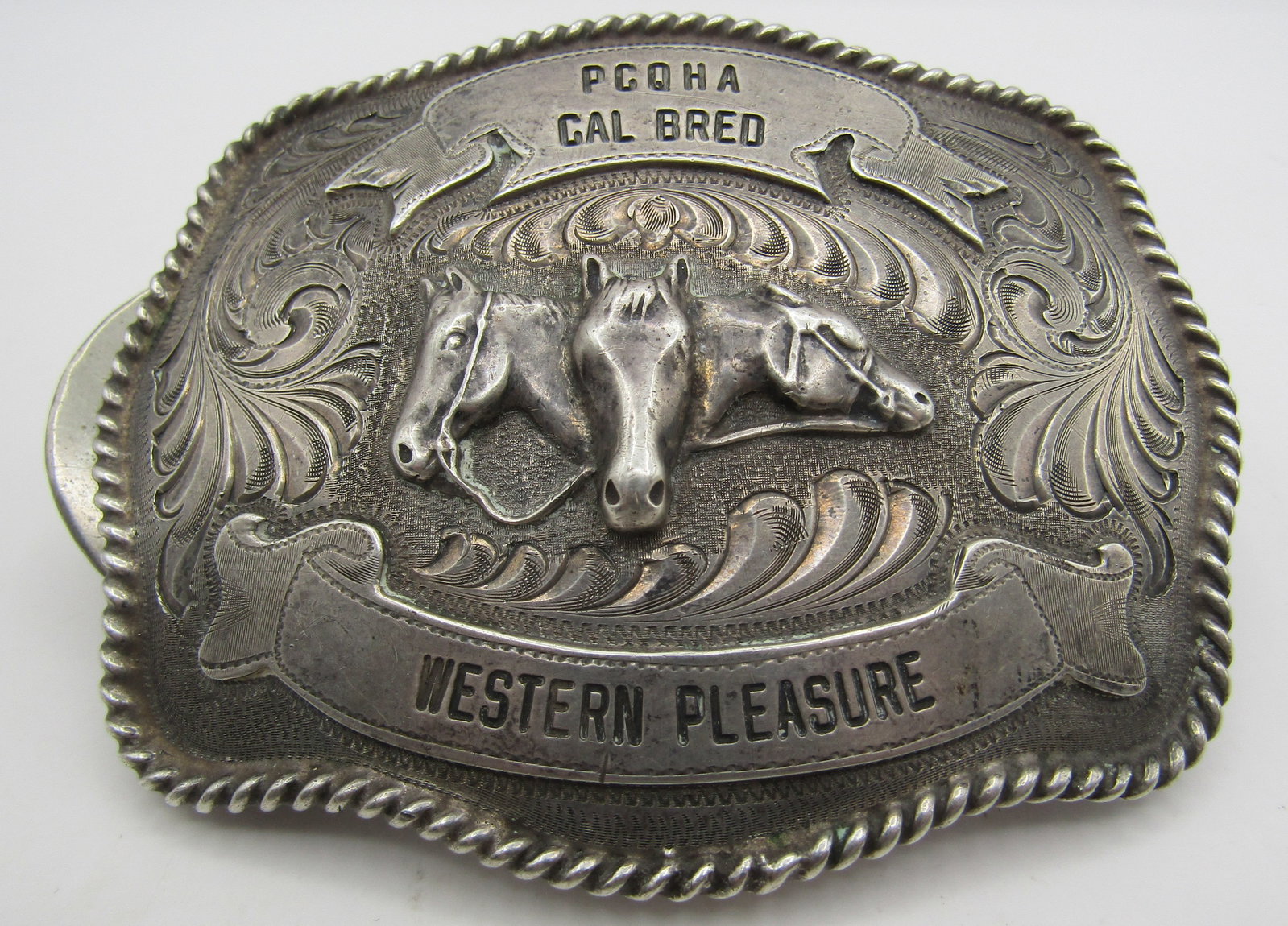 WAGE 122GRAM STERLING SILVER HORSE BELT BUCKLE: THROPHY, AN ORNATELY HAND ENGRAVED BELT BUCKLE. PCQHA CAL BREED: WESTERN PLEASURE. PACIFIC COAST QUARTER HORSE ASSOCIATION CALIFORNIA BREED. GENUINE VINTAGE ESTATE MARKED "WAGE AND ENGRAVED STERLING".